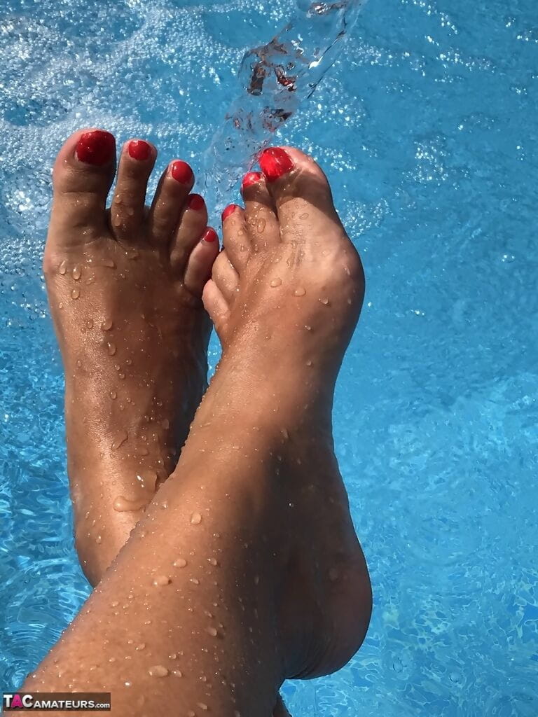 Mature woman Sweet Susi dips her painted toenails into a swimming pool page 1