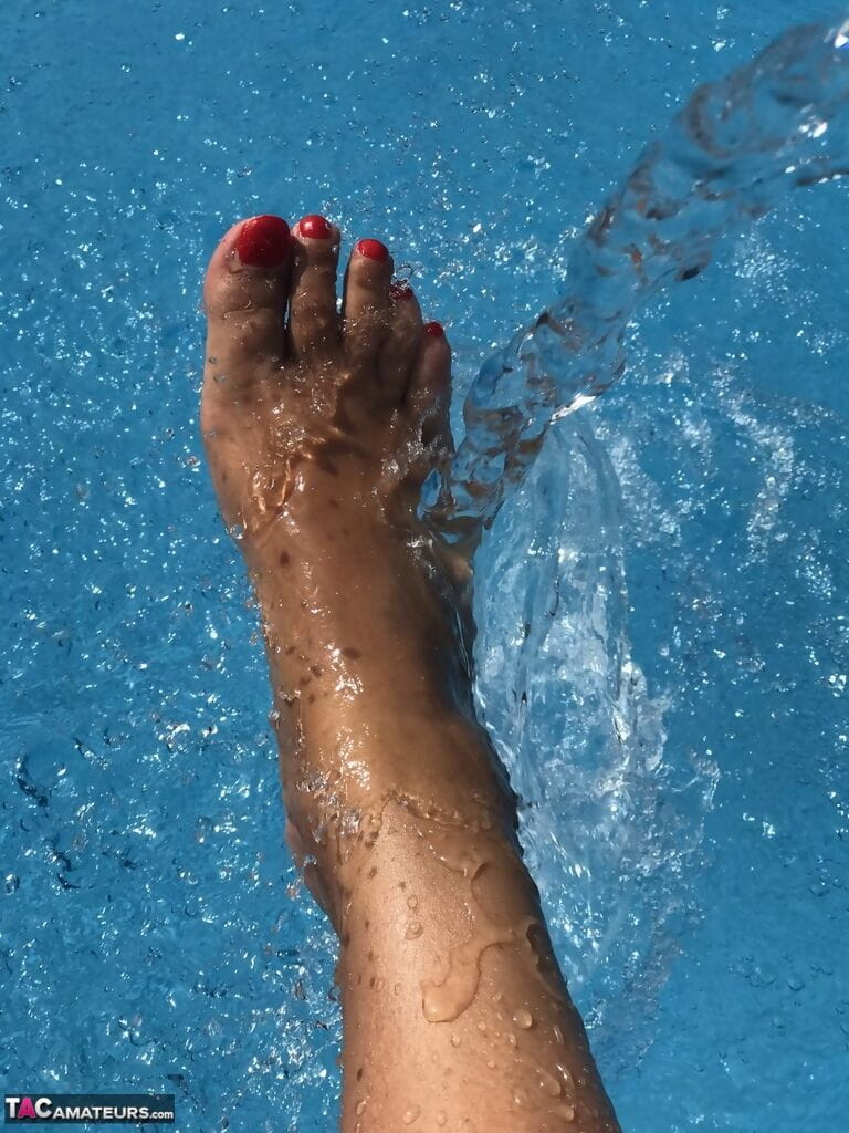 Mature woman Sweet Susi dips her painted toenails into a swimming pool page 1