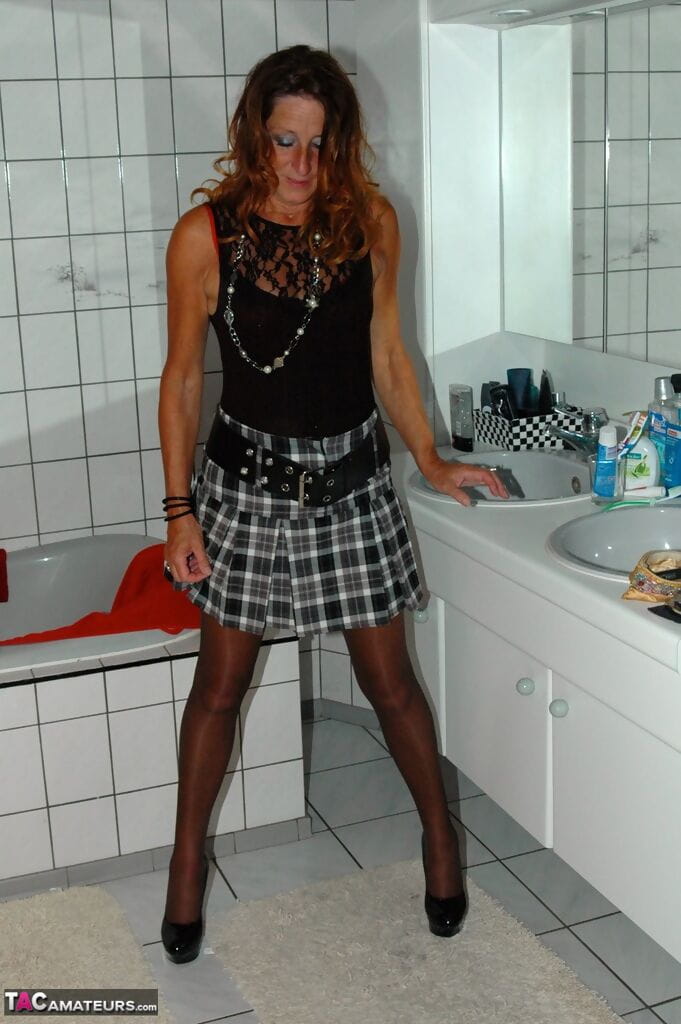 Mature redhead Kyras Nylons hikes her skirt over her pantyhose in the bathroom page 1