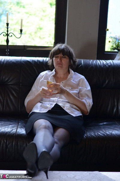 ناضجة امرأة يعرض لها الثدي و كس في حين الشرب النبيذ على الجلود الأريكة