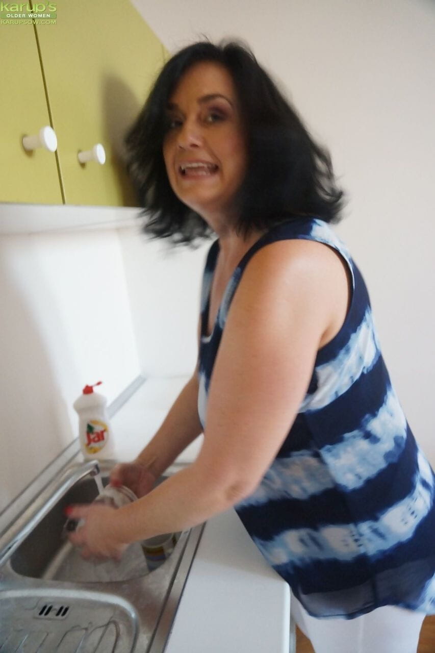 Older housewife Ria Black strips after washing up dishes to finger her pussy page 1
