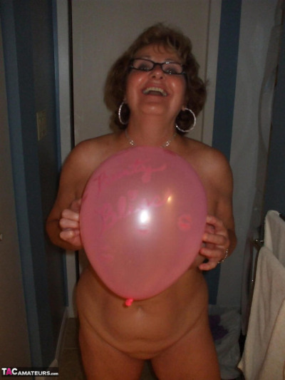 Mature lady models totally naked while playing with balloons