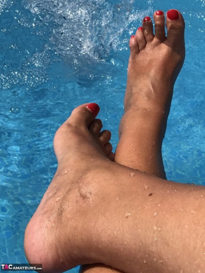 परिपक्व महिला मिठाई susi dips उसके चित्रित toenails के में एक तैराकी पूल